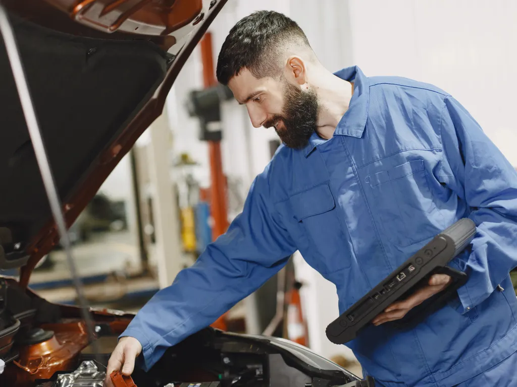 Garajda teşhis cihazıyla aracın motorunu kontrol eden teknisyen