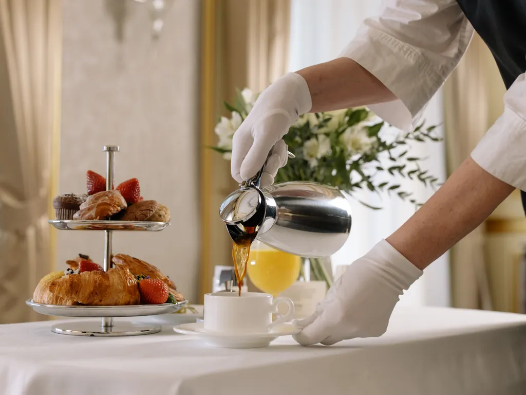 Otel kahvaltı servisinde fincana kahve dolduran garson
