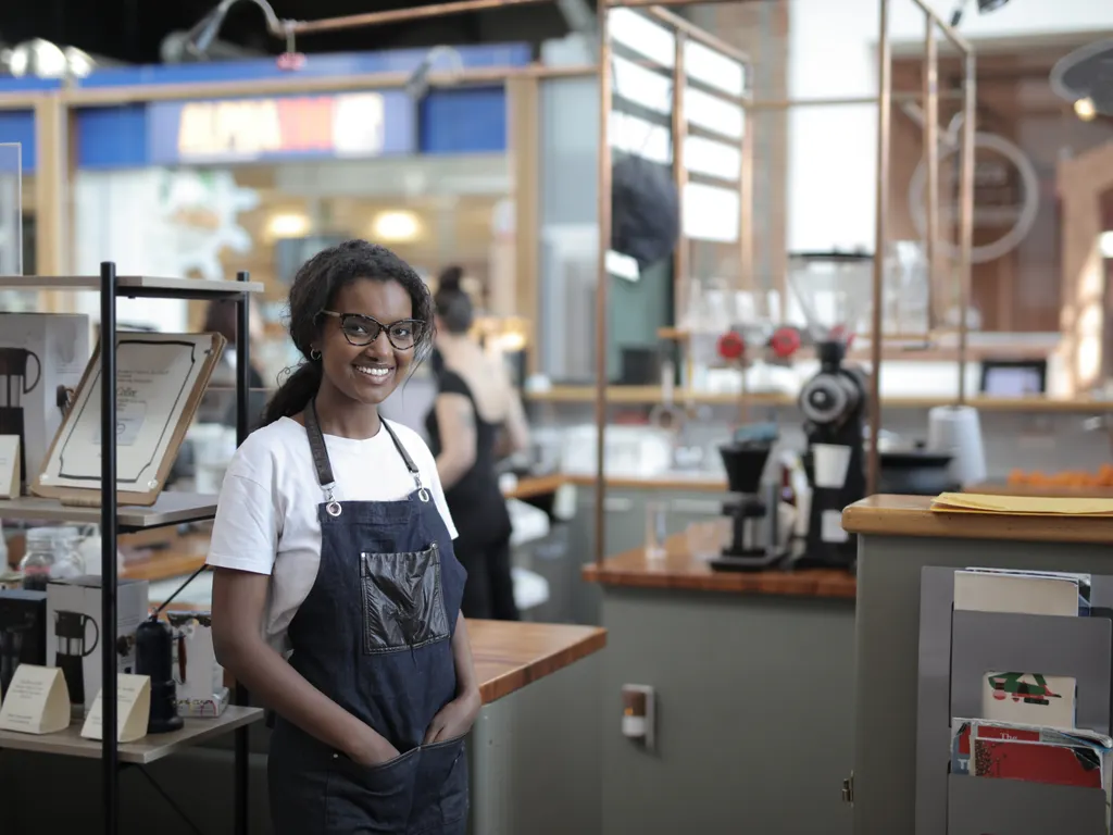 Tezgâhın önünde gülümseyen önlüklü barista