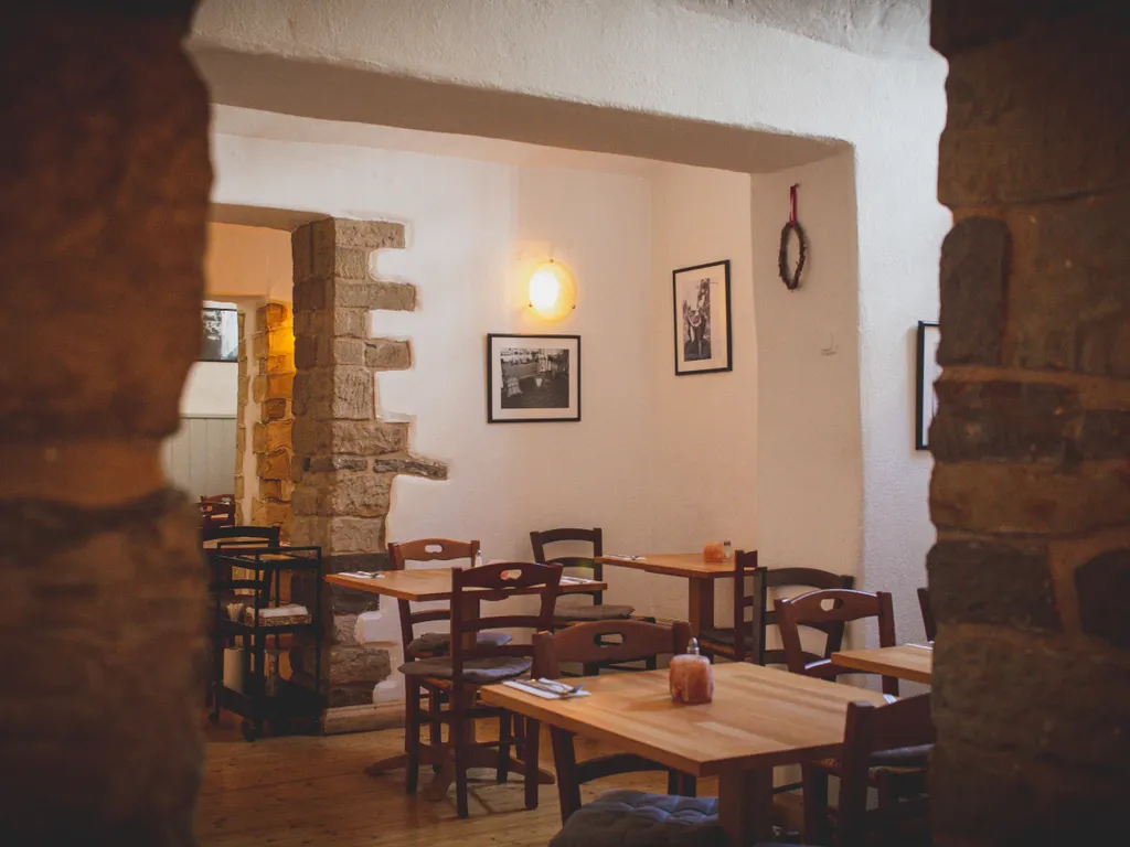Taş duvarlı küçük bir restoranın ahşap masalı salonu